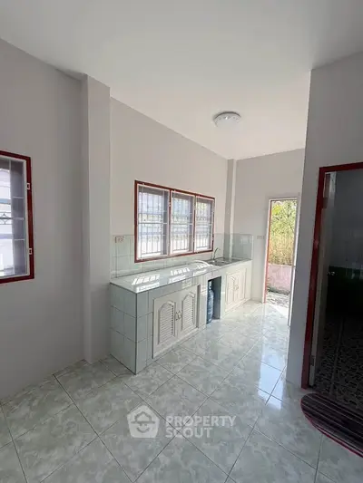 Bright kitchen with tiled floor and ample natural light, featuring a closed layout and modern design.