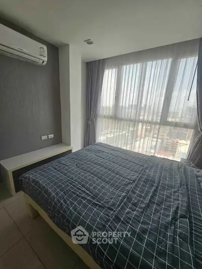 Spacious bedroom with large windows offering stunning city views, perfect for urban living.