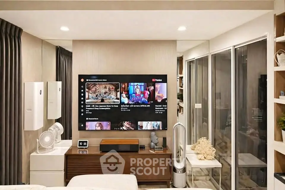 Modern living room with large TV, sleek furniture, and stylish decor in a cozy apartment.