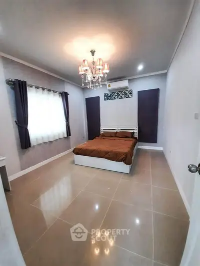 Spacious bedroom with elegant chandelier and modern decor