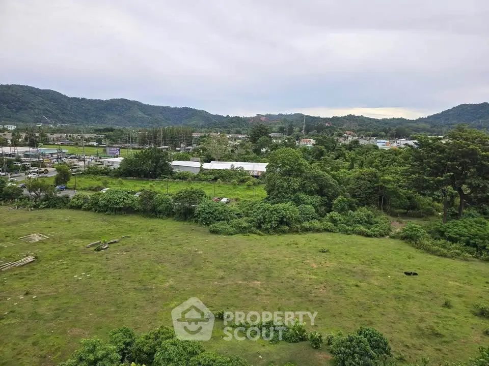 Scenic view of lush green landscape with distant hills and urban development, ideal for real estate investment.