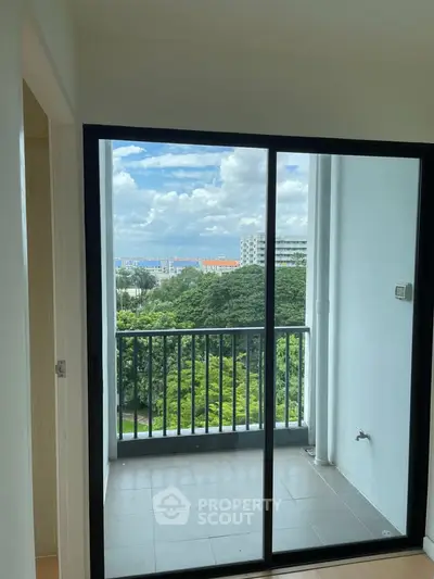 Bright apartment balcony with stunning green view and sliding glass doors.