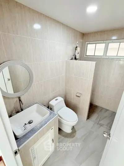 Modern bathroom with sleek fixtures and neutral tiles, featuring a compact layout.