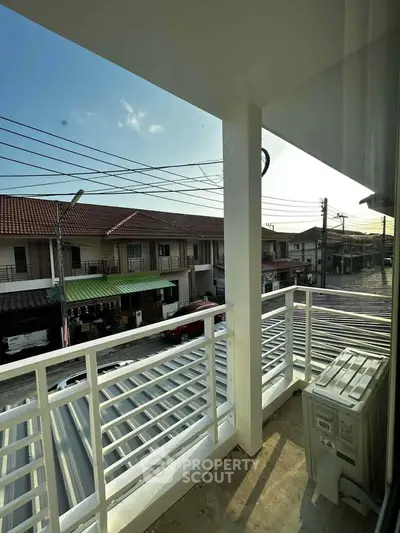 Charming balcony view overlooking residential street with modern railing and air conditioning unit.