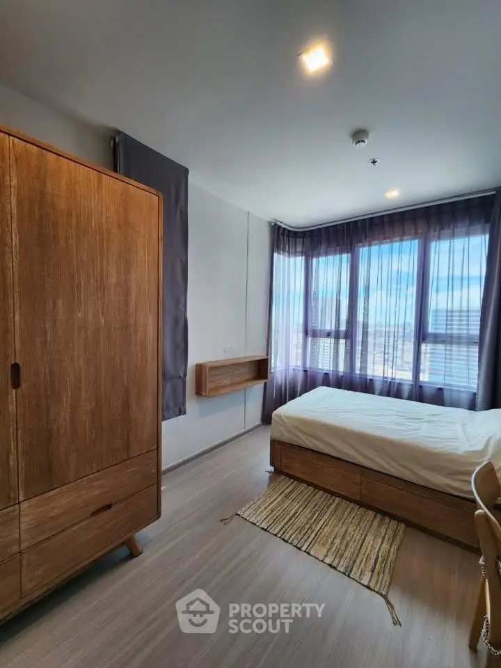 Modern bedroom with large windows and wooden furniture, offering a bright and cozy atmosphere.