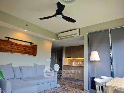 Modern living room with stylish decor and open kitchen layout, featuring a cozy sofa and ceiling fan.