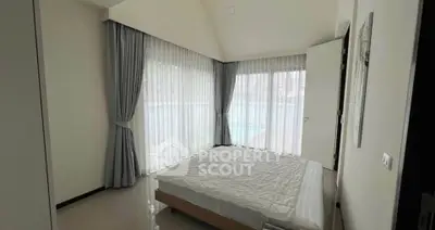 Spacious bedroom with large windows and elegant curtains in modern home