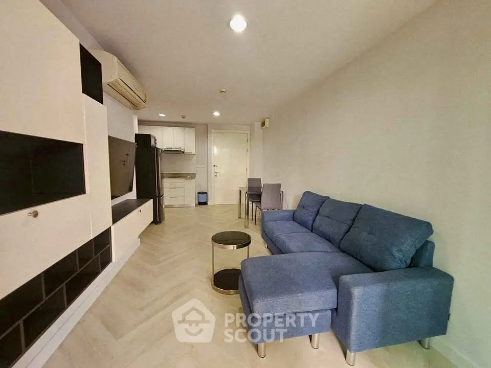 Modern living room with blue sofa and open kitchen layout in stylish apartment.