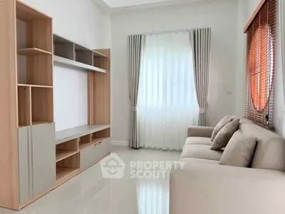 Modern living room with sleek shelving and cozy sofa, featuring elegant curtains and bright natural light.
