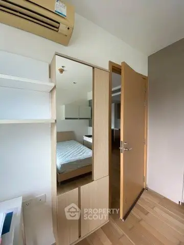 Modern bedroom with wooden flooring and built-in wardrobe, featuring air conditioning for comfort.