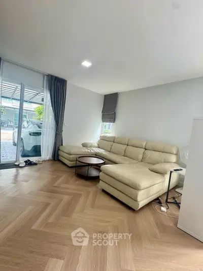 Spacious living room with modern beige sectional sofa and large windows for natural light.