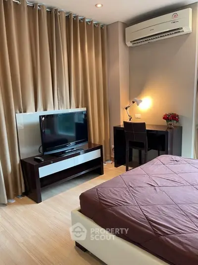 Modern bedroom with TV, desk, and air conditioning in stylish apartment.