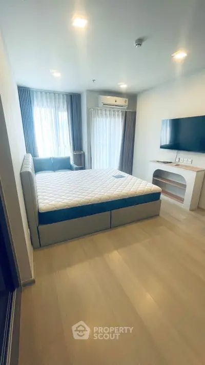 Spacious bedroom with modern furnishings and large windows for natural light.