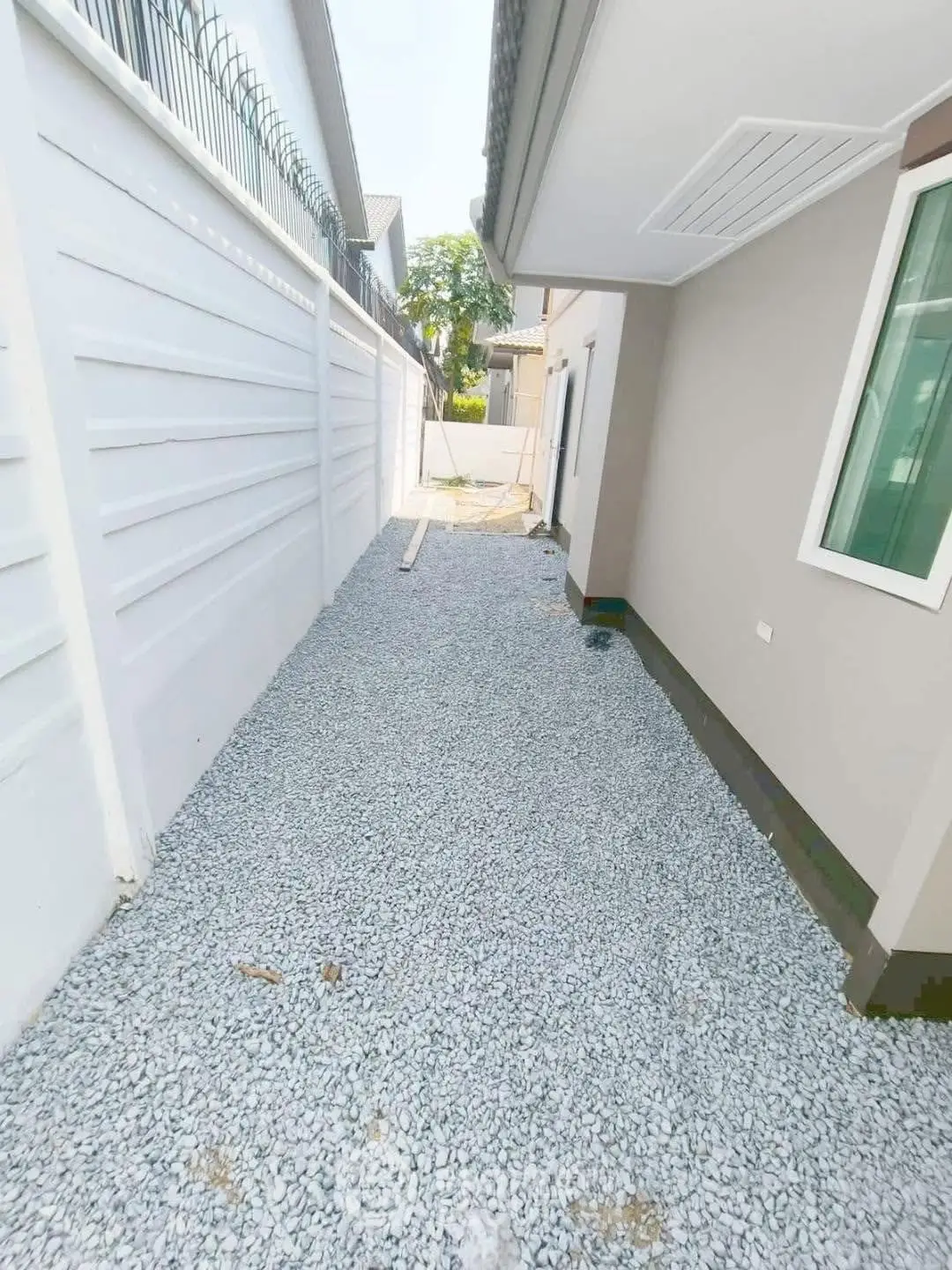 Modern residential exterior with gravel pathway and secure fencing