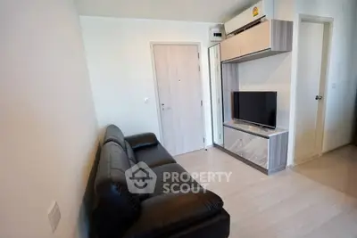 Modern living room with sleek black leather sofa and wall-mounted TV unit.