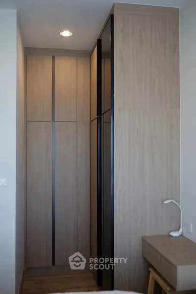 Modern bedroom with sleek wooden wardrobe and minimalist desk lamp