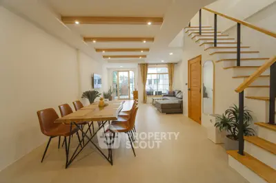 Spacious modern living room with dining area and stylish staircase, featuring elegant decor and ample natural light.