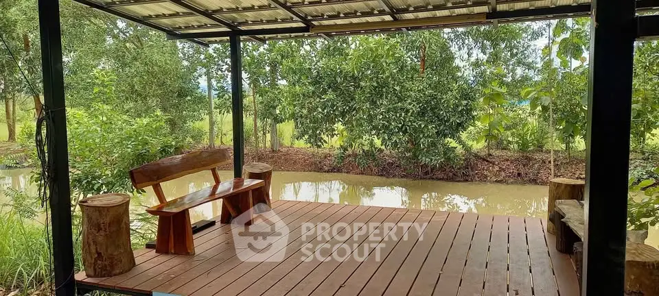Charming wooden deck overlooking serene pond and lush greenery, perfect for relaxation and nature lovers.