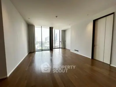 Spacious modern living room with large windows and wooden flooring, offering a bright and airy ambiance.
