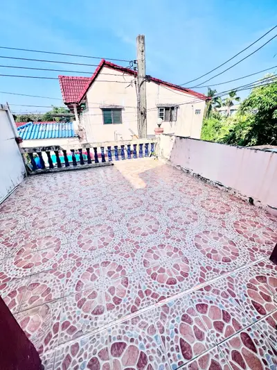 Spacious tiled balcony with scenic view of neighboring houses and clear blue sky.