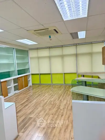 Spacious office space with wooden flooring and ample natural light, ideal for professional use.