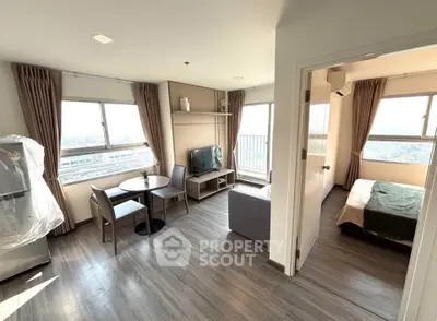 Modern apartment with open living room and bedroom, featuring large windows and stylish furnishings.