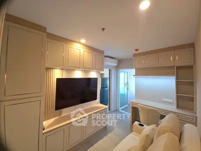 Modern living room with built-in cabinets and large TV, featuring a cozy workspace and bright lighting.