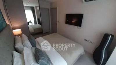 Cozy bedroom with modern decor, wall-mounted TV, and mirrored closet doors.
