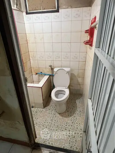 Compact bathroom with tiled walls and floor, featuring a toilet and small bathtub.