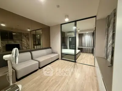 Modern living room with sleek design and glass partition leading to bedroom