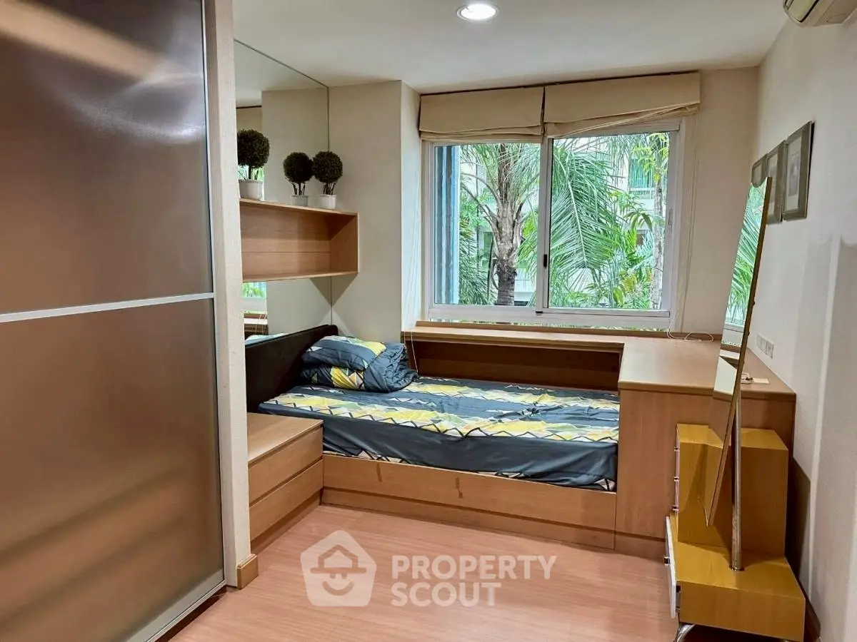 Cozy bedroom with modern furnishings and large window view of lush greenery.