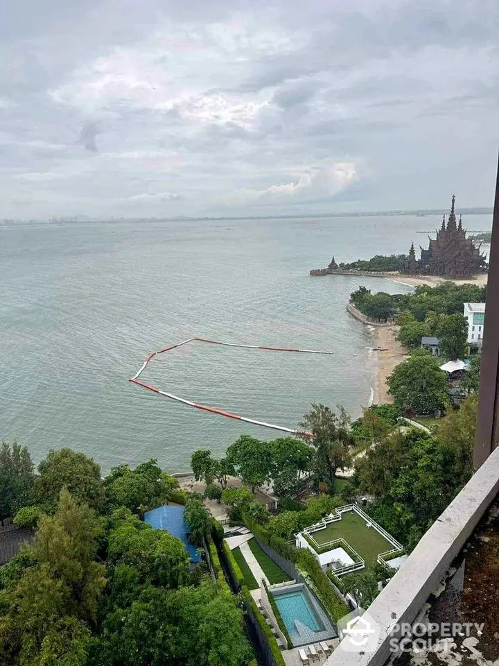 Stunning ocean view from high-rise balcony overlooking lush gardens and distant landmark.