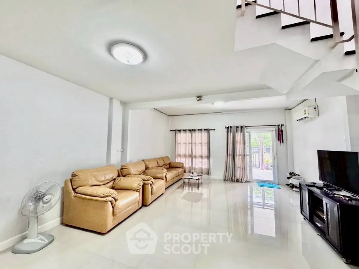 Spacious living room with leather sofas and modern decor in a bright, airy home.