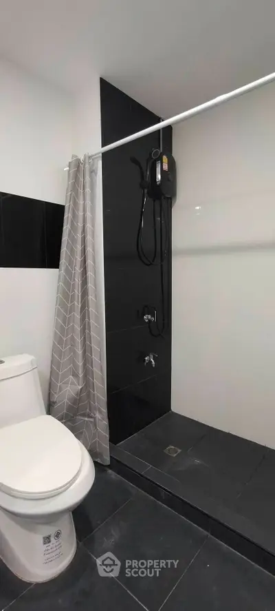 Modern bathroom with sleek black and white tiles and shower area.