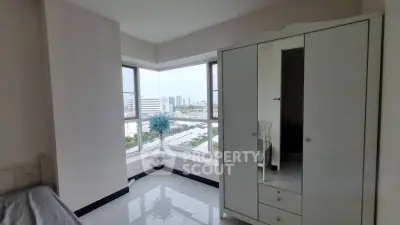 Bright bedroom with large windows offering a stunning city view, featuring a sleek white wardrobe.