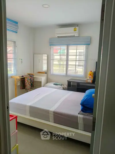 Cozy bedroom with air conditioning and ample natural light, perfect for relaxation and comfort.