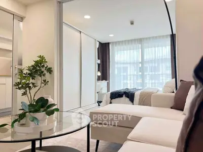 Modern living room with cozy white sofa and natural light, adjacent to a stylish bedroom.