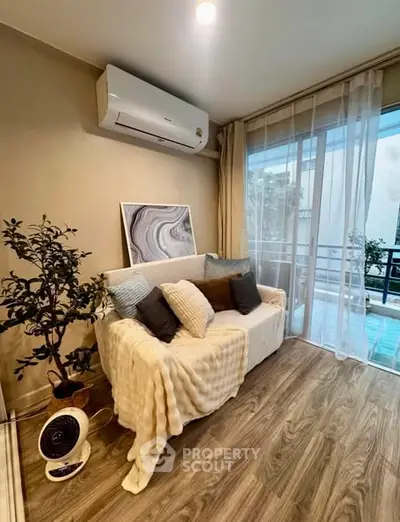Cozy living room with modern decor and balcony view, featuring a comfortable sofa and air conditioning.