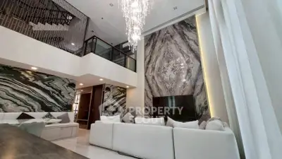Luxurious living room with high ceilings, elegant chandelier, and stunning marble accent wall.