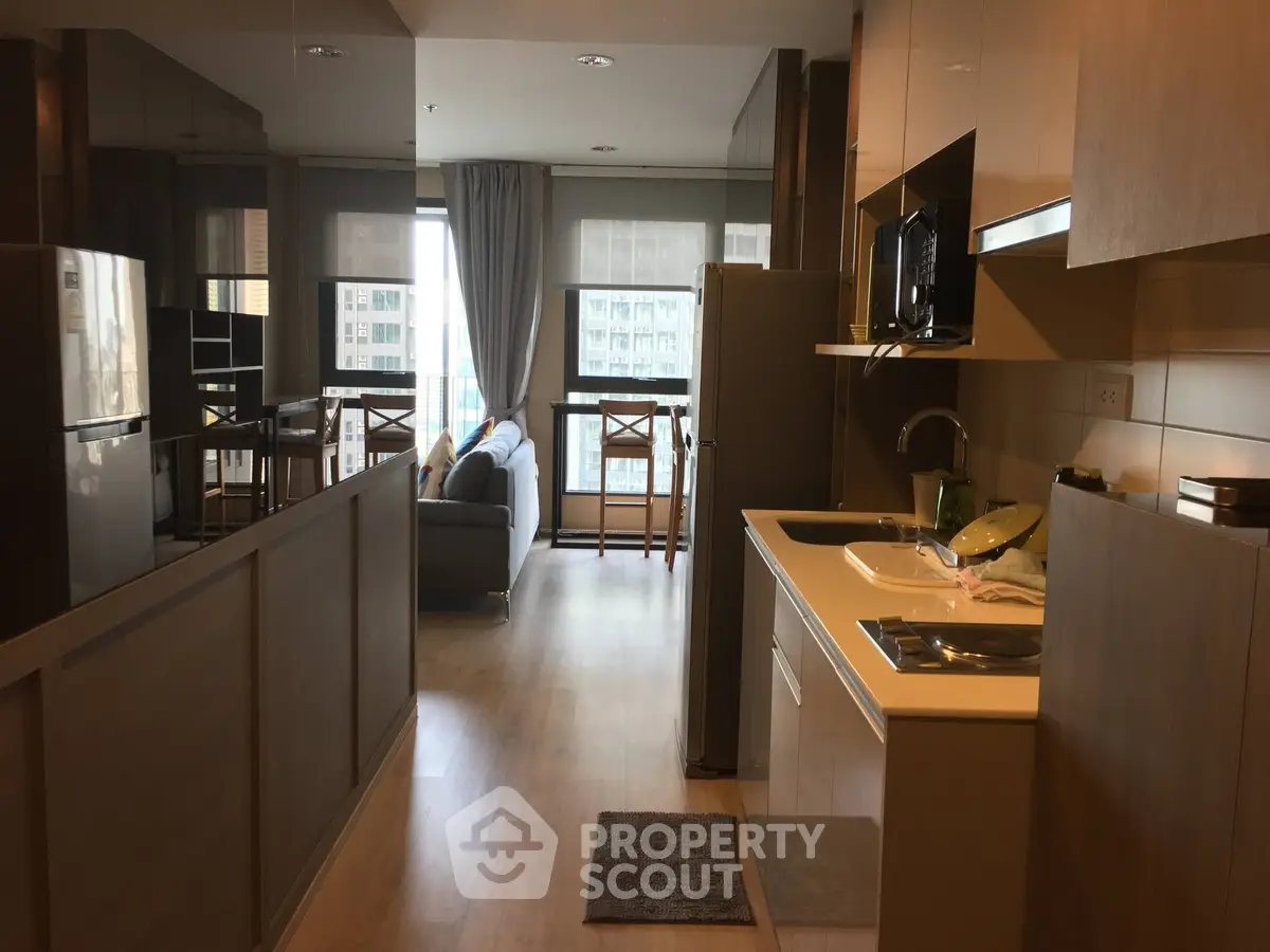 Modern open-layout kitchen and living room with natural light and stylish furnishings.