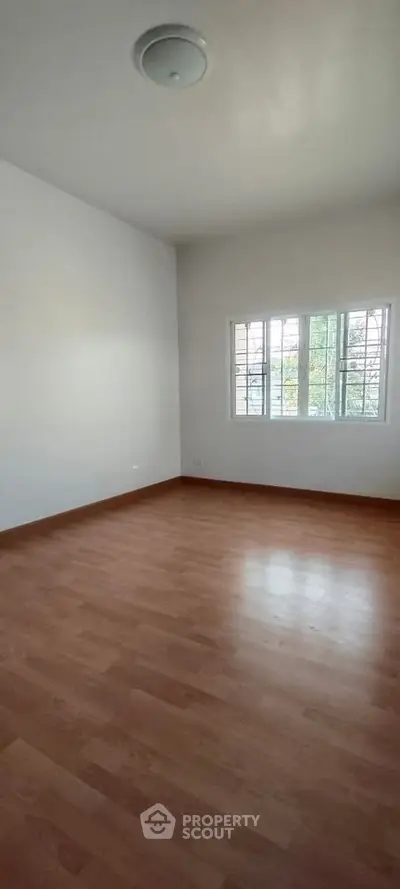 Spacious empty room with wooden flooring and large window