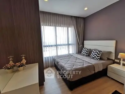 Modern bedroom with stylish decor and large window offering natural light.