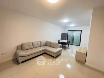 Spacious modern living room with sleek furniture and dining area in open layout.