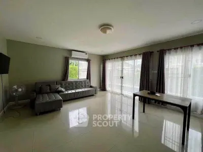 Spacious living room with modern sofa and large windows offering natural light.