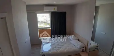 Cozy bedroom with large window and modern decor, perfect for urban living.