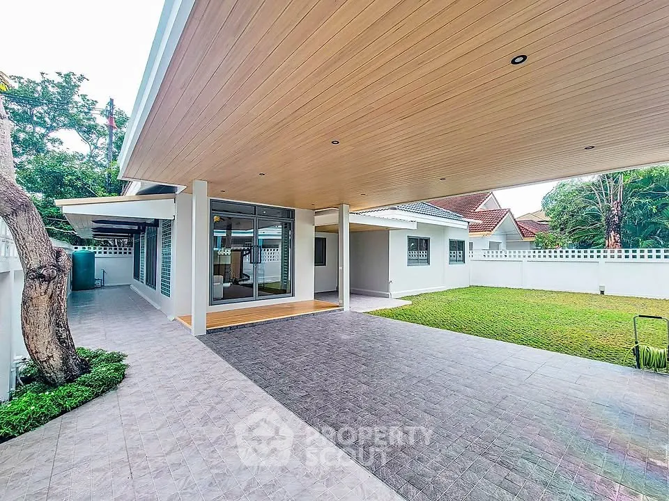 Spacious modern home with covered patio and lush green lawn, perfect for outdoor living.