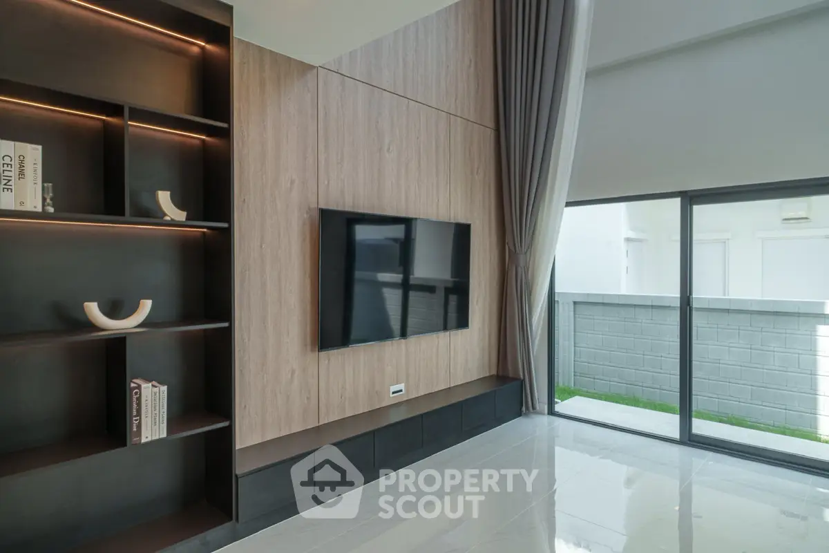 Modern living room with sleek design, large window, and built-in shelving unit.