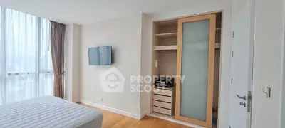 Modern bedroom with built-in closet and wall-mounted TV in a bright apartment.