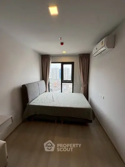 Modern bedroom with city view, featuring a comfortable bed and air conditioning in a high-rise apartment.