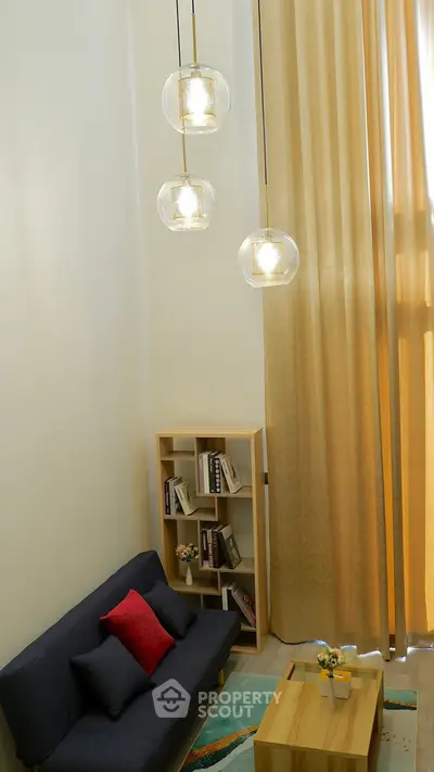 Modern living room with high ceiling, stylish lighting, and cozy seating area.